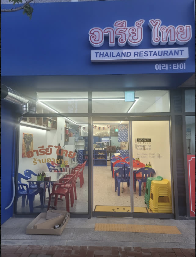 열린 문 너머로 보이는 빨간 의자와 파란 테이블