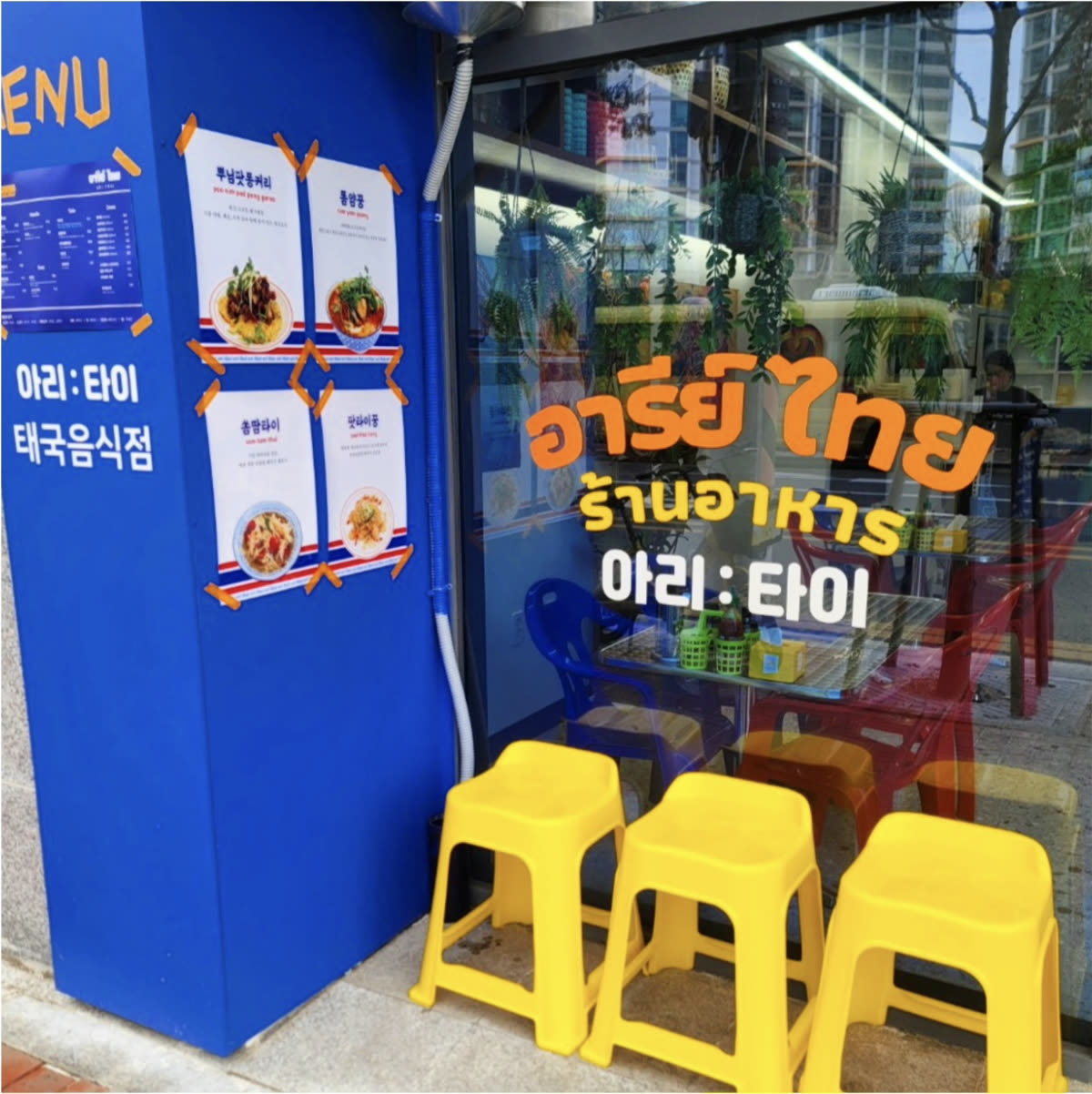 입구 앞에 놓인 노란 플라스틱 스툴 세 개